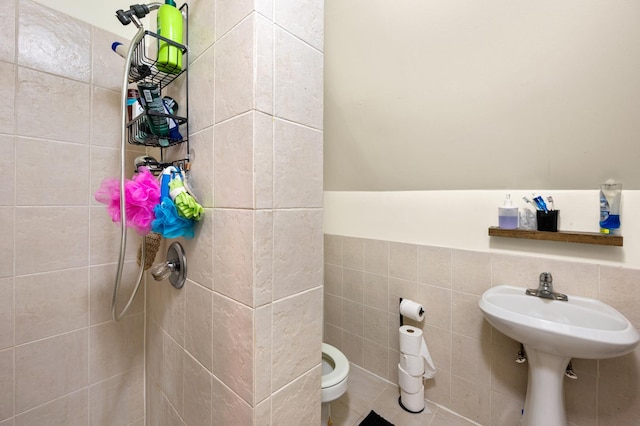 bathroom with tiled shower, toilet, and tile walls