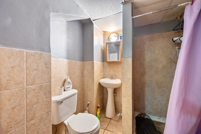 bathroom featuring a paneled ceiling, tile walls, curtained shower, tile patterned floors, and toilet