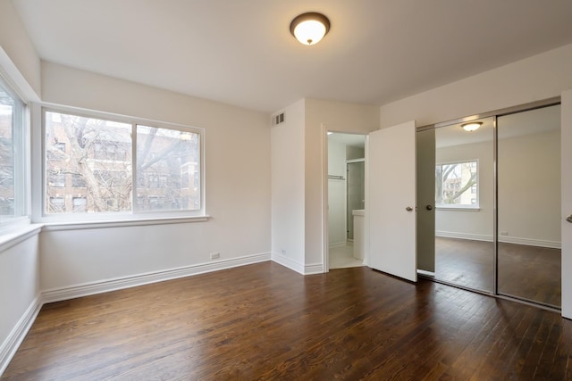 unfurnished bedroom with baseboards, a closet, visible vents, and hardwood / wood-style floors