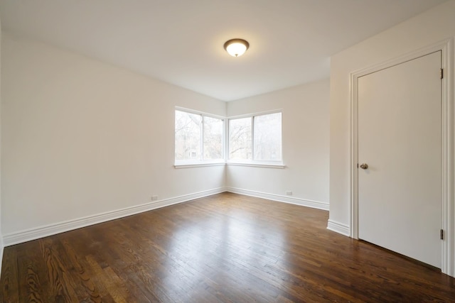 empty room featuring dark wood-type flooring and baseboards