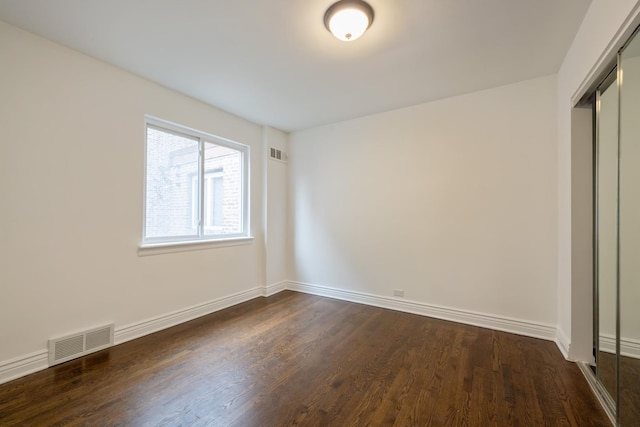 unfurnished bedroom featuring wood finished floors, visible vents, and baseboards