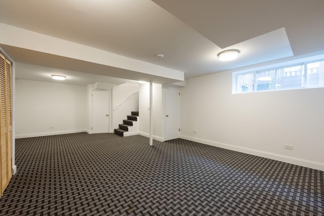 basement with dark colored carpet, stairway, and baseboards