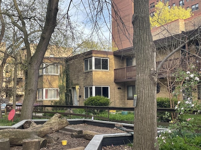 rear view of property with brick siding and a balcony