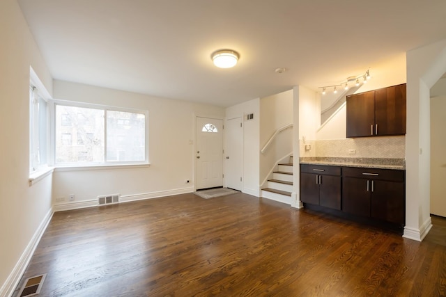 kitchen featuring dark wood-type flooring, visible vents, dark brown cabinetry, and backsplash