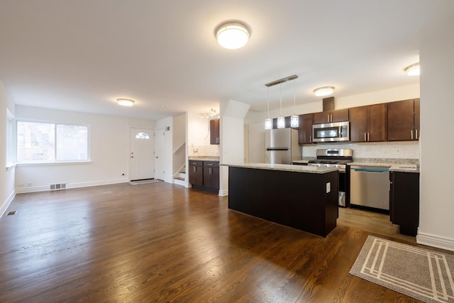 kitchen with visible vents, a kitchen island, appliances with stainless steel finishes, open floor plan, and dark brown cabinets