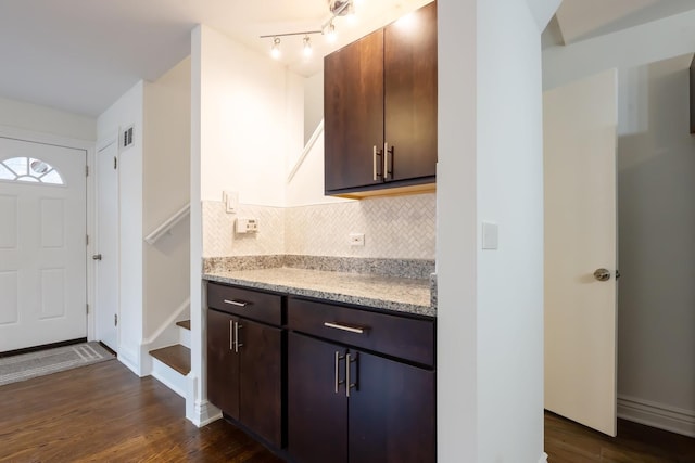 kitchen with dark brown cabinets, backsplash, dark wood finished floors, and baseboards