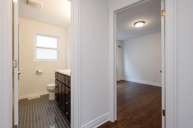 bathroom with toilet, visible vents, vanity, and baseboards