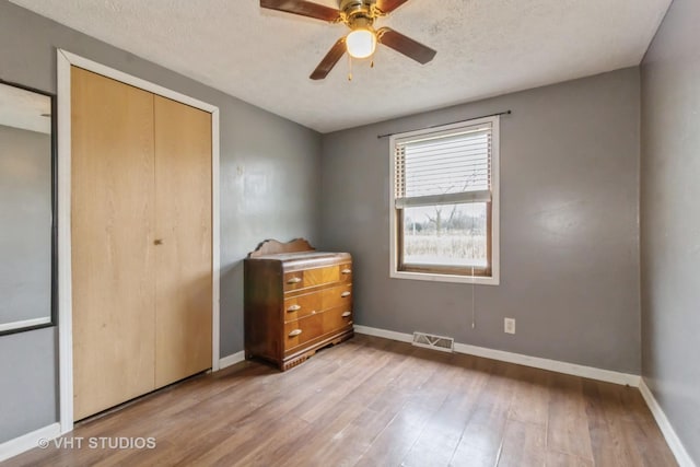 bedroom featuring ceiling fan, light hardwood / wood-style floors, a closet, and a textured ceiling