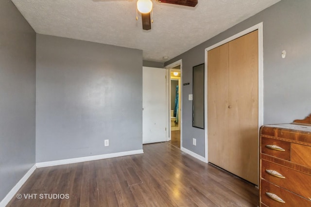 unfurnished bedroom with ceiling fan, a textured ceiling, dark hardwood / wood-style flooring, and a closet