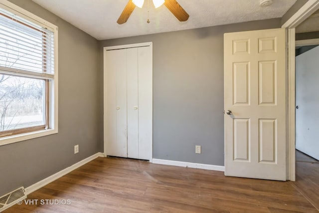 unfurnished bedroom featuring ceiling fan, hardwood / wood-style flooring, a closet, and a textured ceiling