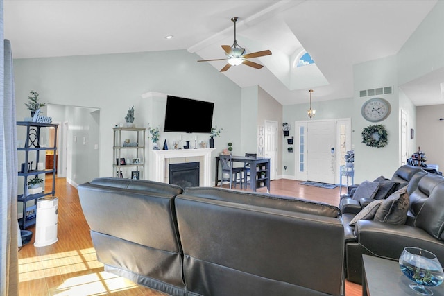 living room featuring high vaulted ceiling, light hardwood / wood-style flooring, beamed ceiling, ceiling fan, and a fireplace