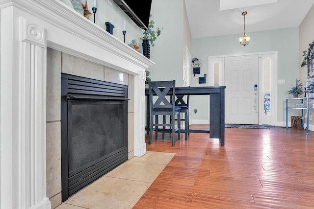 entryway featuring a tile fireplace, hardwood / wood-style floors, and a chandelier