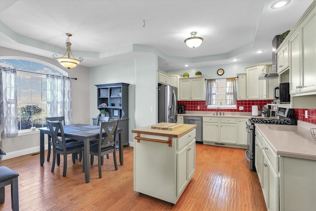 kitchen featuring butcher block countertops, decorative light fixtures, tasteful backsplash, a center island, and stainless steel appliances