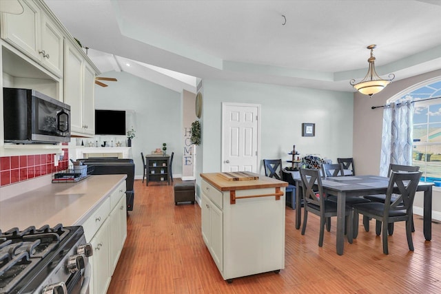 kitchen with butcher block counters, white cabinetry, a center island, light hardwood / wood-style flooring, and pendant lighting