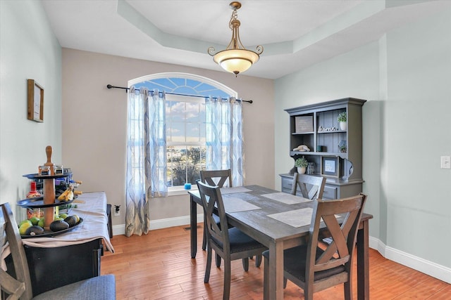 dining area featuring hardwood / wood-style flooring and a tray ceiling