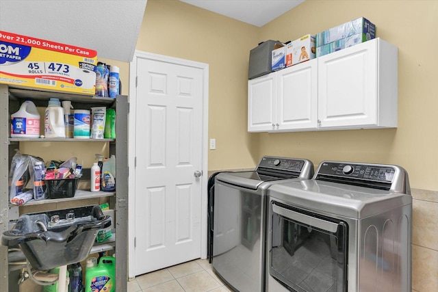 clothes washing area with light tile patterned floors, cabinets, and washer and dryer