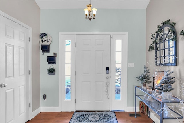 foyer featuring wood-type flooring, a wealth of natural light, and a chandelier