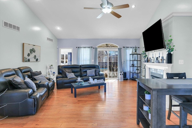 living room with a tiled fireplace, hardwood / wood-style flooring, high vaulted ceiling, and ceiling fan