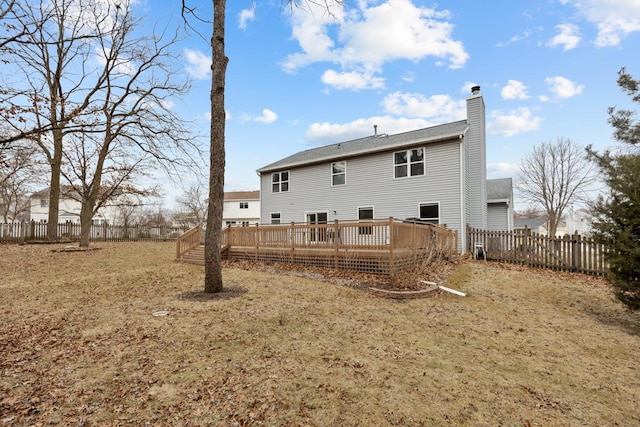 rear view of house featuring a wooden deck and a lawn