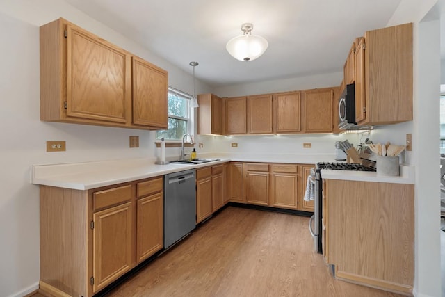 kitchen featuring sink, light brown cabinets, light wood-type flooring, pendant lighting, and stainless steel appliances