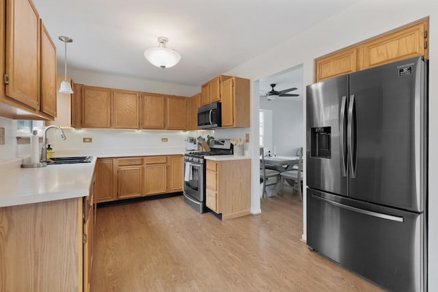 kitchen with sink, decorative light fixtures, light hardwood / wood-style flooring, and stainless steel appliances