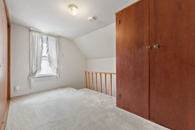 bonus room with vaulted ceiling and light carpet