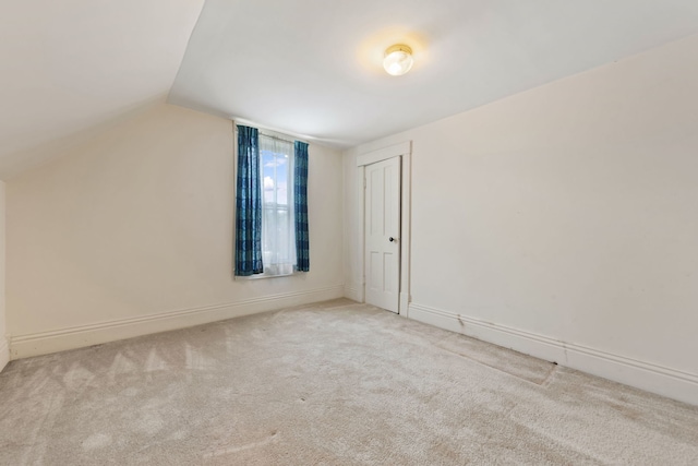 bonus room with vaulted ceiling and light carpet