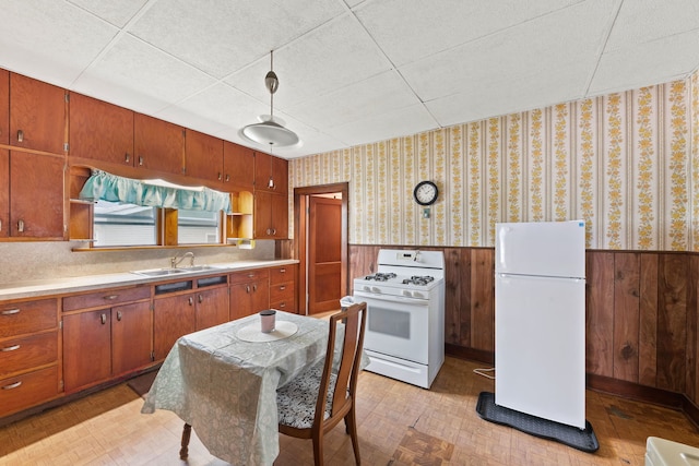 kitchen featuring white appliances, sink, and a drop ceiling