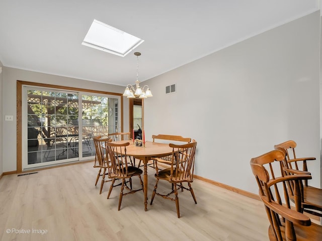 dining room with a chandelier, a skylight, and light wood-type flooring