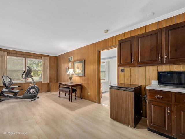 workout room featuring light hardwood / wood-style flooring, ornamental molding, and wooden walls