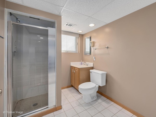 bathroom with tile patterned flooring, vanity, a drop ceiling, toilet, and walk in shower