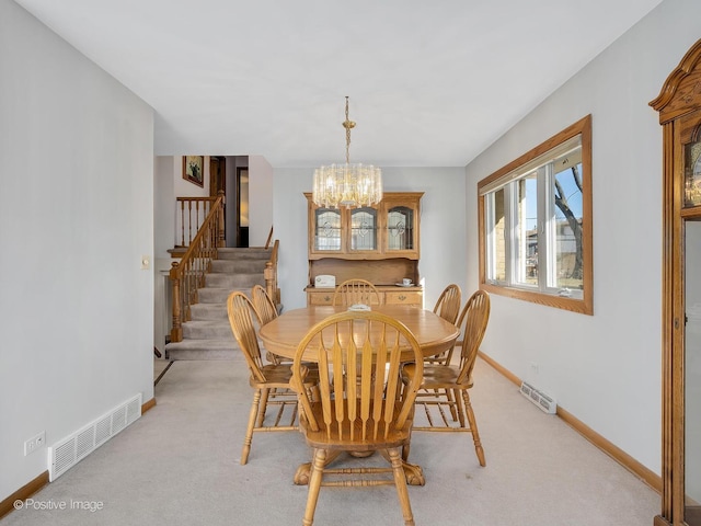 carpeted dining area with a chandelier