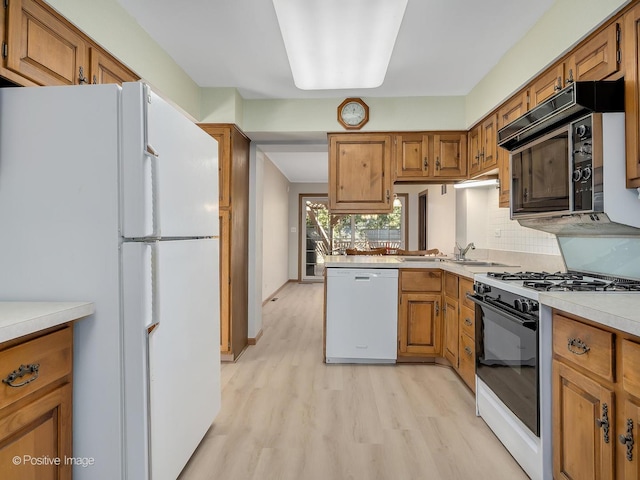 kitchen with backsplash, white appliances, light hardwood / wood-style flooring, and sink