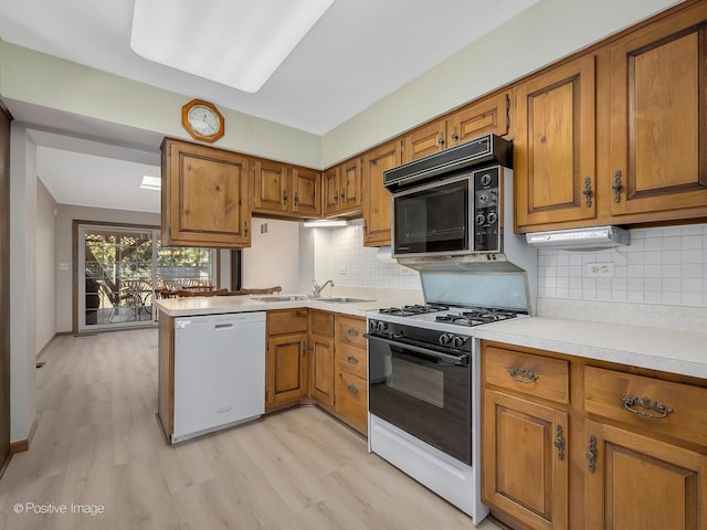 kitchen featuring sink, dishwasher, range with gas stovetop, kitchen peninsula, and light wood-type flooring