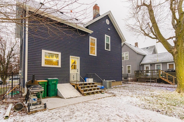 snow covered back of property featuring central air condition unit