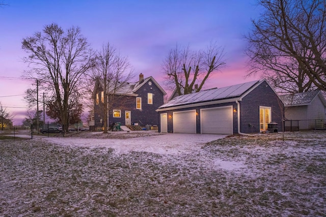 view of front of home with a garage, an outdoor structure, and solar panels