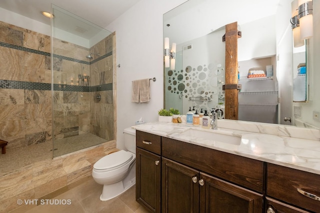 bathroom with tiled shower, tile patterned floors, toilet, vanity, and decorative columns