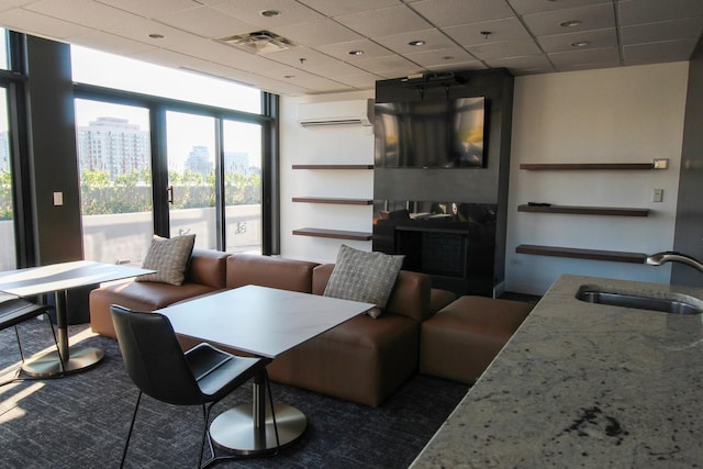 dining space featuring floor to ceiling windows, a wall mounted AC, sink, and a drop ceiling