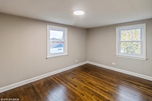 empty room with plenty of natural light and dark hardwood / wood-style floors