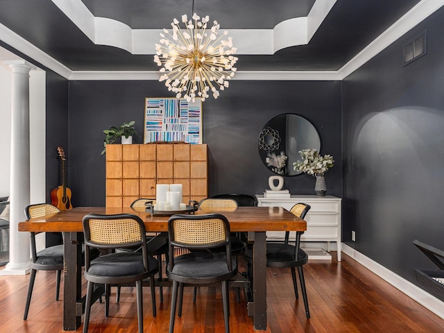 dining area with decorative columns, an inviting chandelier, ornamental molding, a raised ceiling, and hardwood / wood-style floors