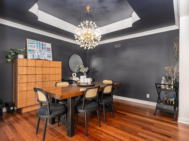 dining space with crown molding, a notable chandelier, a tray ceiling, and hardwood / wood-style floors