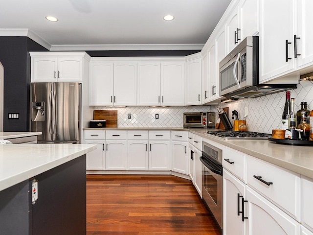 kitchen with stainless steel appliances, white cabinetry, ornamental molding, and dark wood-type flooring