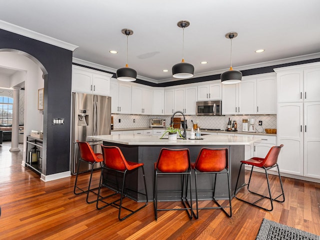 kitchen featuring white cabinetry, appliances with stainless steel finishes, a kitchen bar, and an island with sink