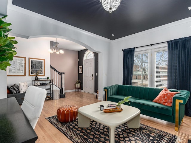 living room with wood-type flooring, a notable chandelier, and crown molding