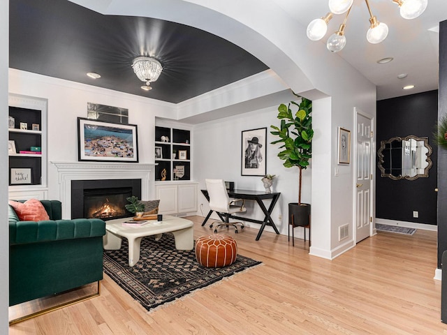 living room featuring a chandelier, built in features, and light wood-type flooring