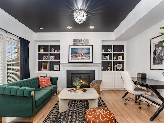 office space with crown molding, a fireplace, built in shelves, and hardwood / wood-style floors