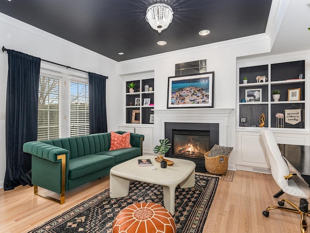 living room featuring ornamental molding, a fireplace, light wood-type flooring, and built in shelves