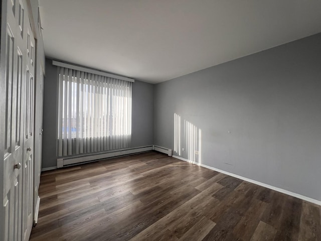 empty room featuring a baseboard radiator and dark hardwood / wood-style floors