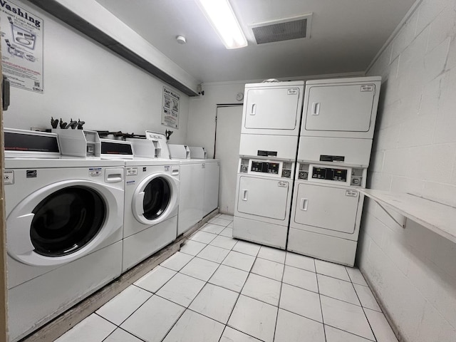 laundry area with light tile patterned flooring, washing machine and clothes dryer, and stacked washer / drying machine