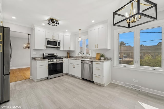 kitchen with white cabinetry, decorative light fixtures, and stainless steel appliances